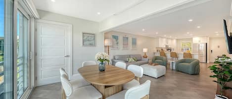 A spacious living area with a dining table, sofas, and a kitchen in the background.