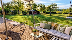 Eine Terrasse im Freien mit einem weißen Sofa und einem Tisch, umgeben von einer Holzterrasse und einem überdachten Bereich.