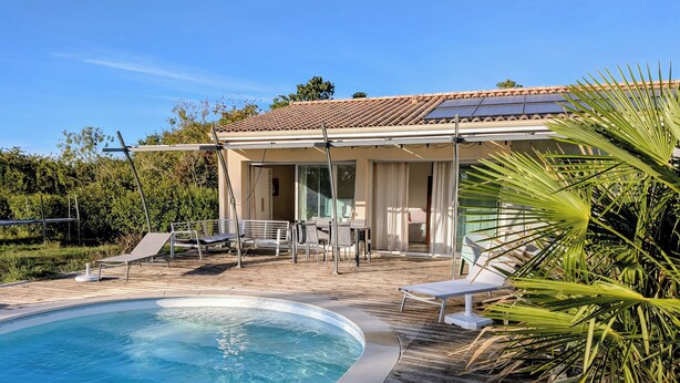 Ein Schwimmbecken mit Liegestühlen und einer überdachten Terrasse.