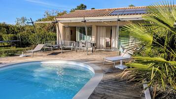 A swimming pool with lounge chairs and a covered patio area.