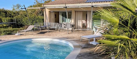 A swimming pool with lounge chairs and a covered patio area.