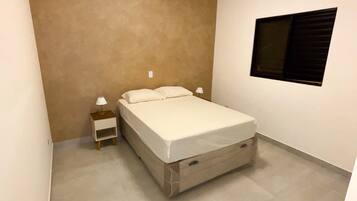 A bedroom with a bed, nightstand, and a window.