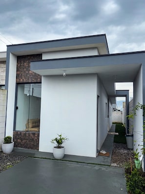 A modern house with a covered walkway, potted plants, and a view of the sky.