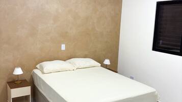 Quarto com cama, duas mesas de cabeceira e uma janela.