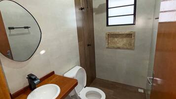 A compact bathroom with a toilet, sink, and mirror.