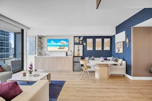 A modern living room with a sofa, coffee table, and a dining area with chairs. - Dreamy 1BR | Skyline Balcony City Views+ Pool, Spa, Gym (Miami)