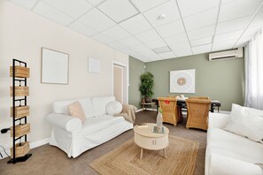 A modern living room with a white sofa, a round coffee table, and a green accent wall. - Vrbo Property (Montpon-Ménestérol)