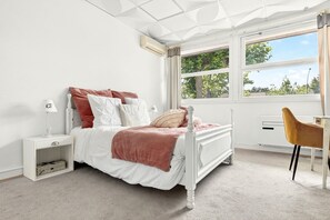 A bedroom with a bed, bedside table, lamp, and a desk with a chair. - Vrbo Property (Montpon-Ménestérol)