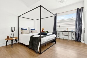 A modern bedroom with a four-poster bed, a desk, and a chair. - Vrbo Property (Montpon-Ménestérol)
