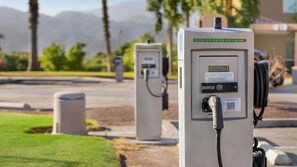 Duas estações de carregamento para veículos elétricos com vista desobstruída da área circundante, incluindo uma estrada e montanhas ao longe.