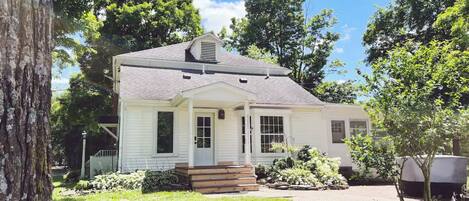 A single-story house with a front porch, a chimney, and a well-maintained lawn.
