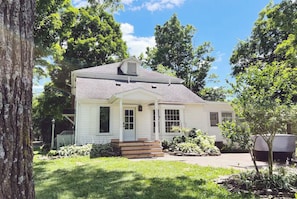 A single-story house with a front porch, a chimney, and a well-maintained lawn.