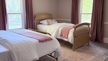 A bedroom with two beds, a large window, and a ceiling light fixture.