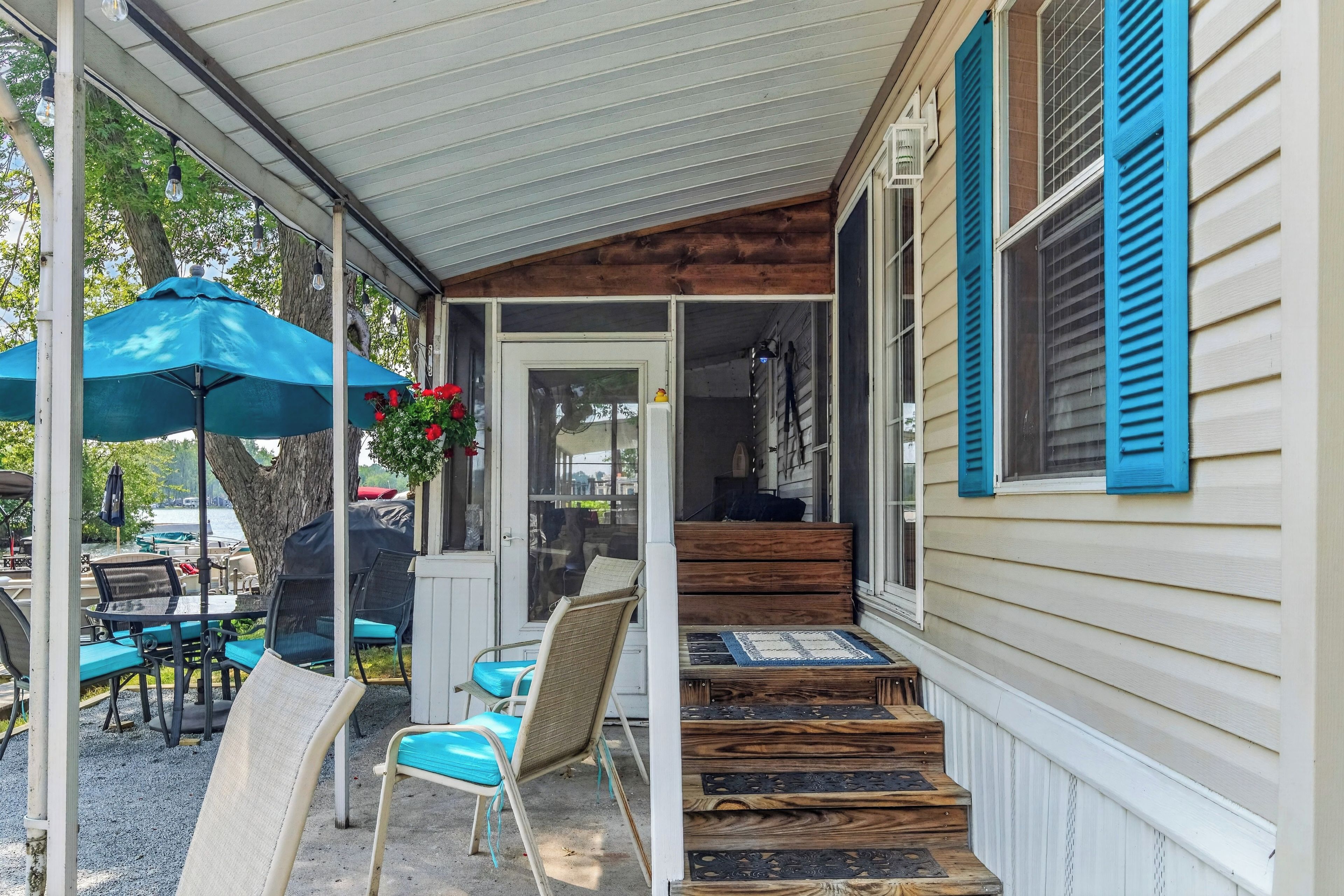 A covered porch with outdoor seating, a wooden staircase, and a view of the water.