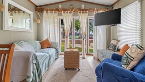 Ein gemütliches Wohnzimmer mit einer Couch, einem Fernseher und einem großen Fenster mit Vorhängen.