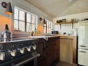 A kitchen with a stove, sink, and refrigerator.