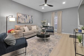 A modern living room with a grey sofa, a blue armchair, a coffee table, and a painting on the wall.
