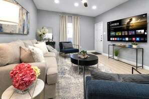 A modern living room with a sofa, armchairs, a coffee table, and a flat-screen TV mounted on the wall. - Julie: 1 Bedroom Apt, 4 minute walk to A&M (College Station)