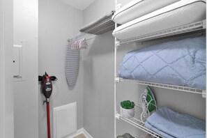 A laundry area with a Shark iron, a drying rack, and a shelf with a plant and folded clothes. - Julie: 1 Bedroom Apt, 4 minute walk to A&M (College Station)