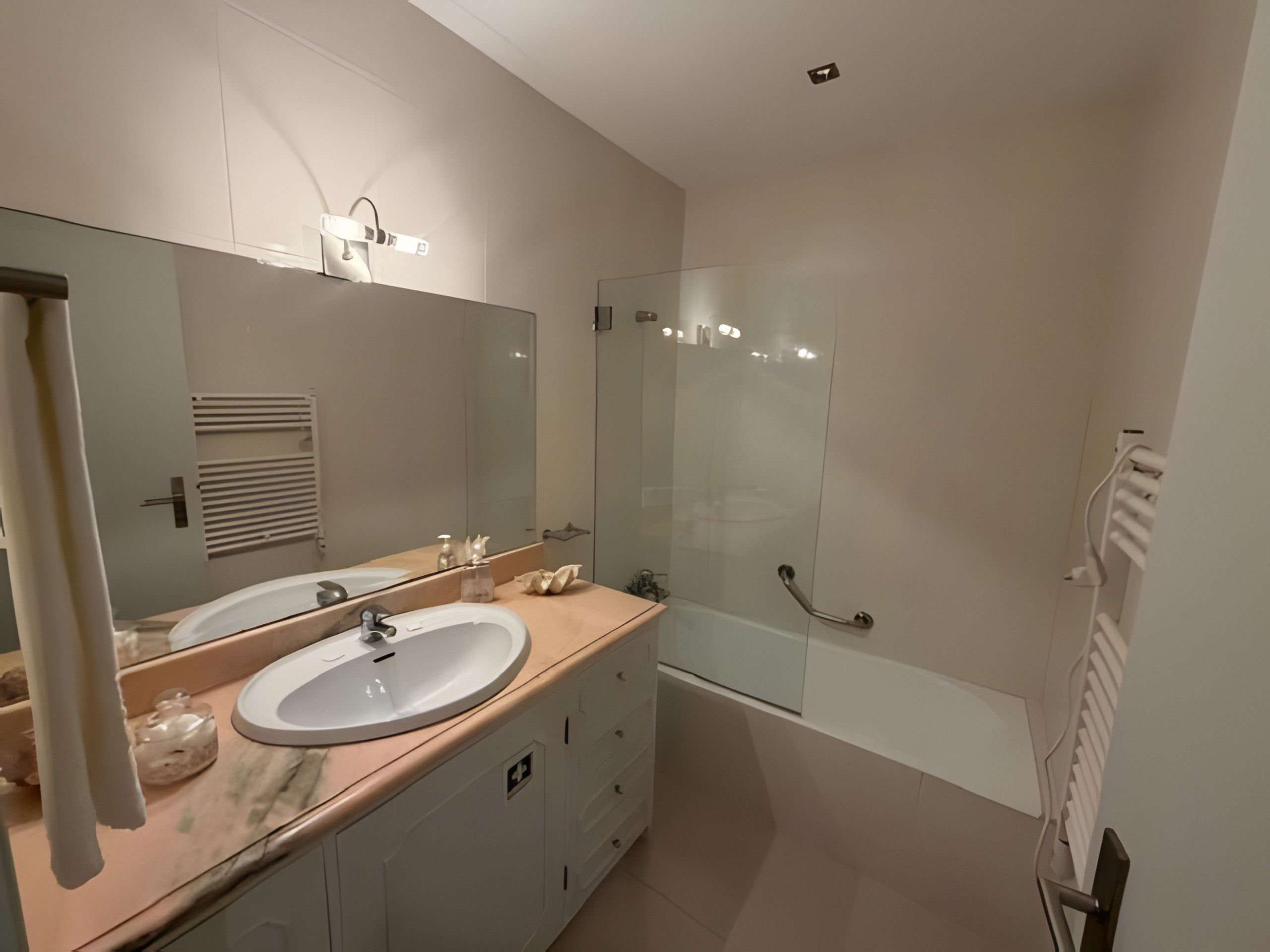A modern bathroom with a double sink vanity, a glass shower enclosure, and a towel rack.