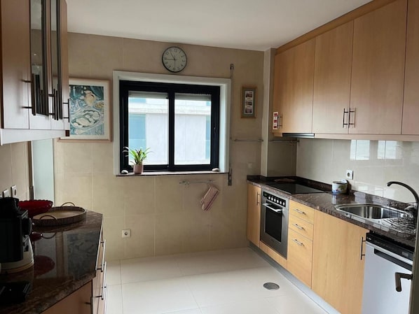 A kitchen with wooden cabinets, a stove, a sink, and a window with a plant on the windowsill.