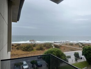 Une vue d’un parking rempli de voitures, d’une plage et d’une côte rocheuse.
