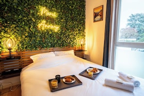 A hotel room with a bed, a neon sign on the wall, and breakfast trays on the bed. - Thank you, Annecy - Private Parking / Near the Lake - Soleidor (Annecy)