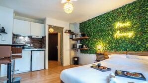 Une chambre d’hôtel moderne avec un lit, un plateau de petit-déjeuner et un mur vert agrémenté d’un néon.