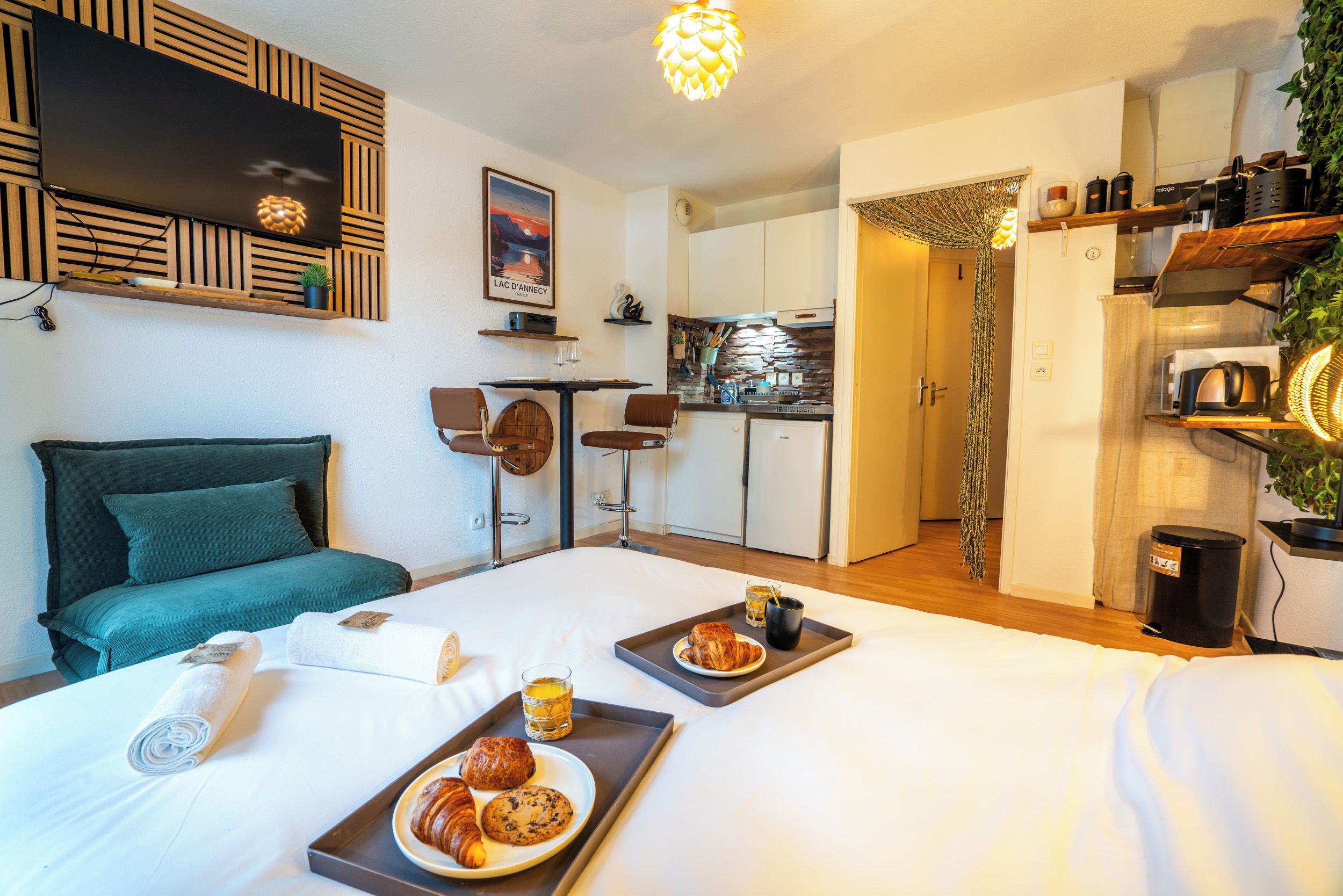 A hotel room with a bed, breakfast tray, and a kitchenette.