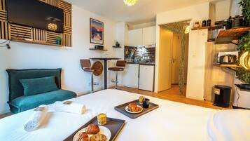 A hotel room with a bed, breakfast tray, and a kitchenette.