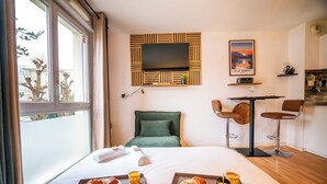 Une chambre d’hôtel avec un lit, un plateau de petit-déjeuner, une télévision et une vue sur l’extérieur.