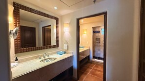 A bathroom with a large mirror, a sink with a towel, and a shower area. - Vrbo Property (Cabo San Lucas, BCS)
