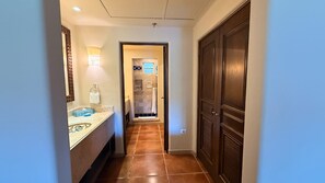 A hallway with a bathroom on the left, a shower area in the middle, and a door on the right. - Vrbo Property (Cabo San Lucas, BCS)