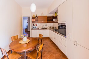 A compact kitchen with a dining table, chairs, and a variety of appliances including a microwave, oven, and sink.