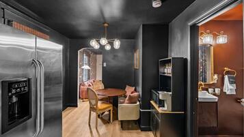 Une cuisine compacte dotée d’un réfrigérateur intégré, d’un coin repas avec une table et des chaises en bois, et d’un petit coin cuisine comprenant un évier et un plan de travail.