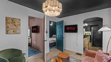 Een moderne hotelkamer met een groot bed, een televisie, een kroonluchter en een schilderij aan de muur.