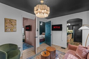 Een moderne hotelkamer met een groot bed, een televisie, een kroonluchter en een schilderij aan de muur.