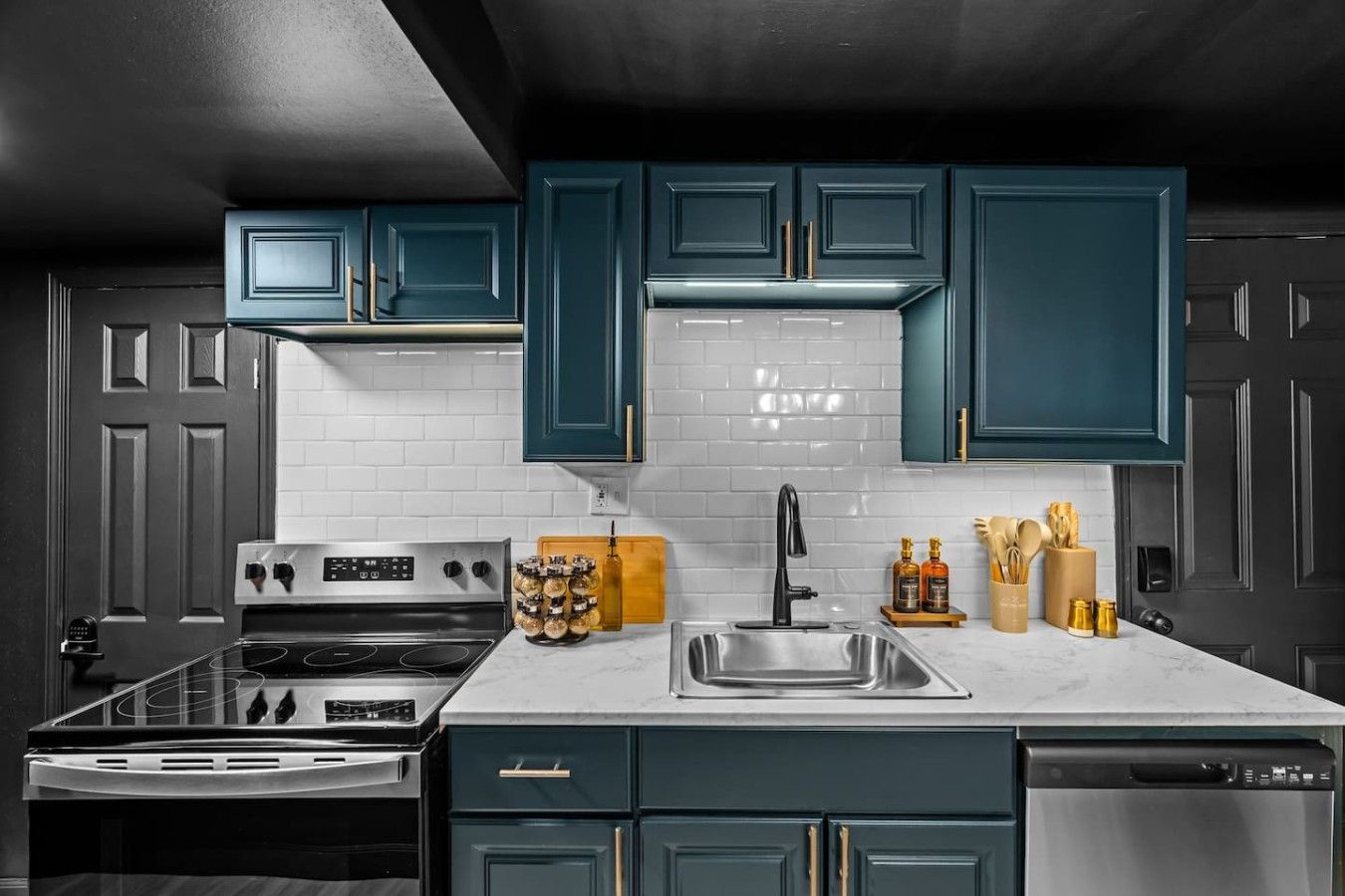 Una cocina con gabinetes color turquesa, salpicadero blanco de azulejos, electrodomésticos de acero inoxidable y una tabla de cortar de madera.