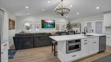 A modern kitchen with white cabinetry, a central island with a sink, and a built-in oven.