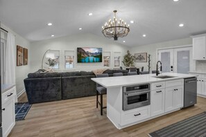 A modern kitchen with white cabinetry, a central island with a sink, and a built-in oven. - Heated Pool - Waterfront - 14 acre - 7bd 6ba (Friendsville)
