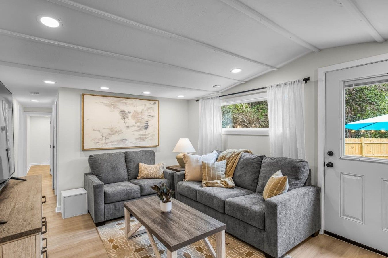 A modern living room with two grey sofas, a wooden coffee table, and a large abstract painting.