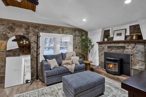 Una sala de estar acogedora con pared de piedra, chimenea, sofá y un espejo grande.