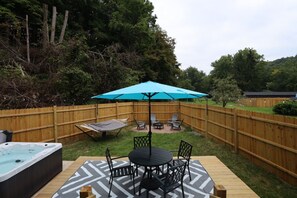 A backyard with a hot tub, a table with chairs, a hammock, and a blue umbrella. - Heated Pool - Waterfront - 14 acre - 7bd 6ba (Friendsville)