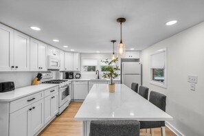 A modern kitchen with white cabinetry, a central island, and pendant lighting. - Heated Pool - Waterfront - 14 acre - 7bd 6ba (Friendsville)