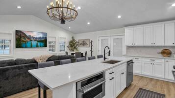 A modern kitchen with white cabinetry, a central island with a sink, and a built-in oven.