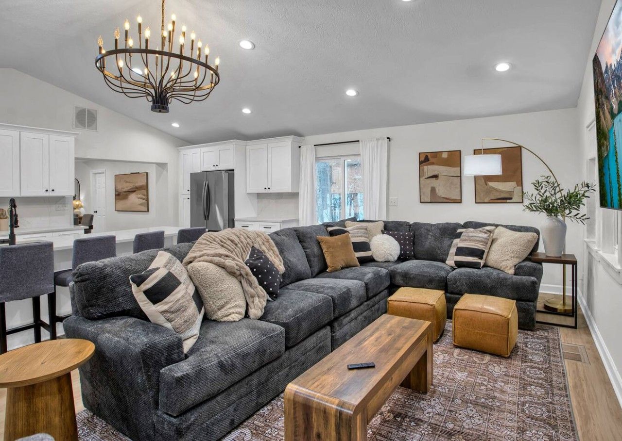 A modern living room with a sectional sofa, wooden coffee table, and a chandelier.