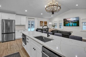 A modern kitchen with a large island, stainless steel appliances, and a chandelier. - Heated Pool - Waterfront - 14 acre - 7bd 6ba (Friendsville)