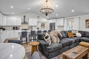 A modern kitchen with white cabinets, a central island, and a dining area with a round table.
