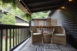 A covered outdoor seating area with wicker furniture and a patterned floor.