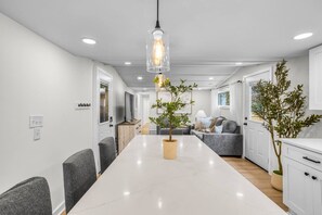 A modern kitchen with white cabinets, a marble countertop, and a hanging pendant light. - Heated Pool - Waterfront - 14 acre - 7bd 6ba (Friendsville)